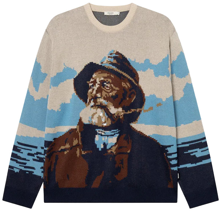 A beige crewneck sweater featuring a large, stylized graphic print of a bearded man in a hat against a blue and beige landscape background, with dark navy sleeves and hem.