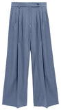 A pair of high-waisted, wide-leg trousers in a dusty slate blue color, featuring pleated detailing down the front and a matching fabric belt, shown against a white background.