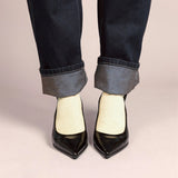 Black shoes, yellow glitter socks, and rolled-up jeans on a plain background
