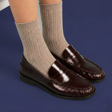 Brown loafers with beige socks on a blue background